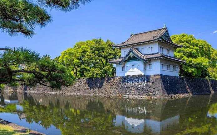 Tokyo Imperial Palace building with surrounding moat and lush greenery.
