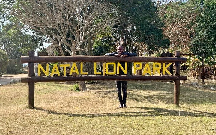 Natal Lion Park entrance sign in Durban with visitor standing behind.