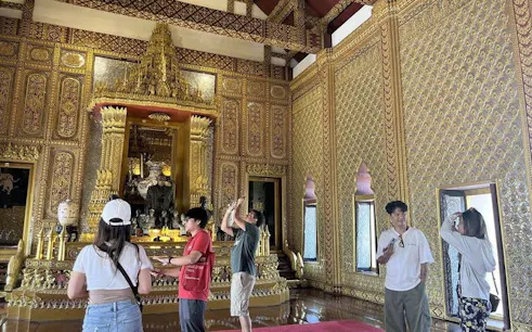 Visitors exploring ornate interior of Erawan Museum in Bangkok.
