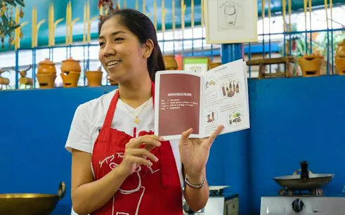 Instructor holding a recipe book at Sompong Thai Cooking School, Bangkok.