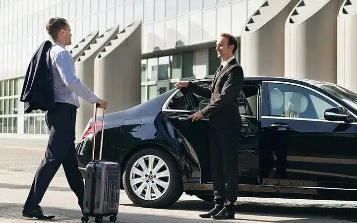 Businessman with luggage approaches a black car for Sharm Airport transfer to Sharm El Sheikh hotel.