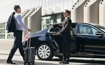 Businessman with luggage approaches a black car for Sharm Airport transfer to Sharm El Sheikh hotel.
