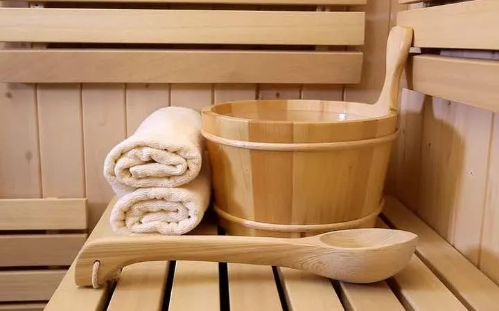 Wooden sauna bucket and ladle with towels in a Hurghada steam bath setting.