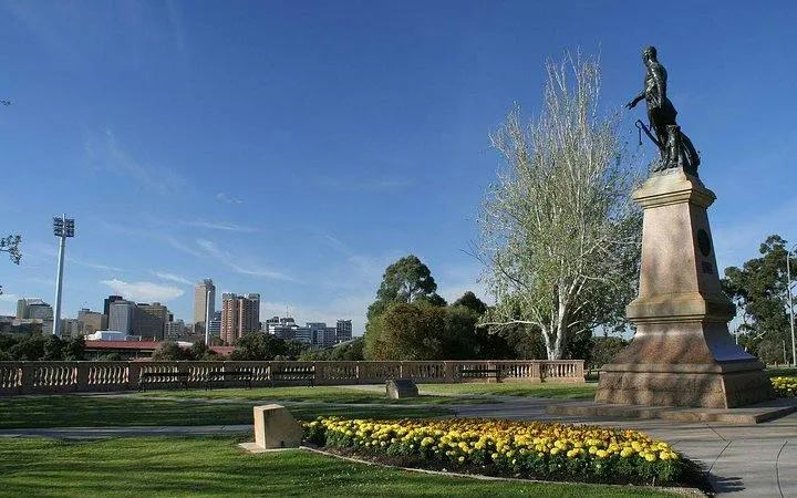 Statue in Adelaide park with city skyline in background, part of self-guided audio tour.