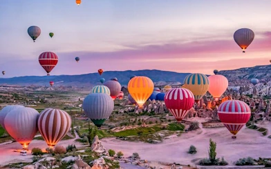 Hot air balloons over Cappadocia landscape at sunrise, Turkey.