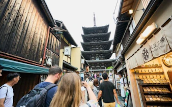 Tourists walking through Kyoto's Gion district with Yasaka Pagoda in view.