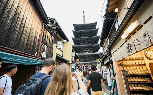 Tourists walking through Kyoto's Gion district with Yasaka Pagoda in view.