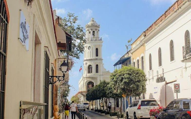 Colonial street in Santo Domingo with historic architecture and a prominent church tower.