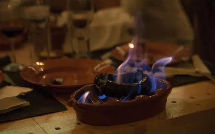 Grilled chorizo on fire at a Portuguese dinner in Lisbon's historic Roman theatre venue.