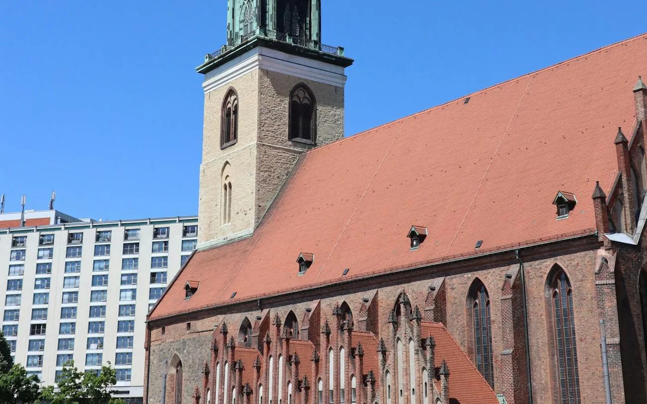St. Nicholas Church in Berlin's Nikolaiviertel with modern buildings in the background.
