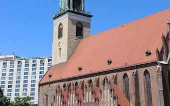 St. Nicholas Church in Berlin's Nikolaiviertel with modern buildings in the background.