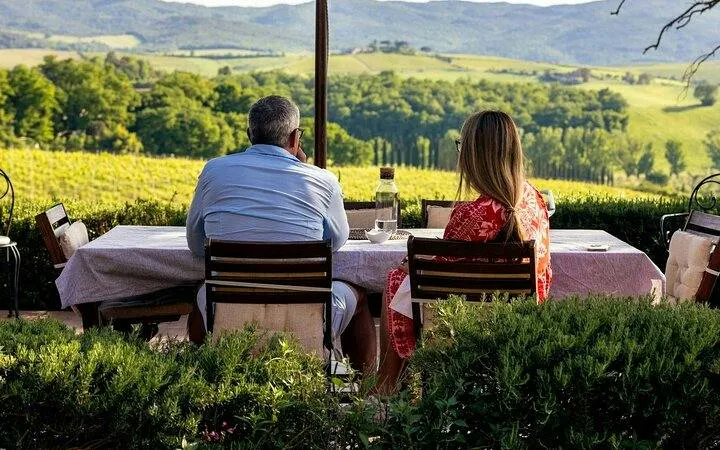 Couple enjoying wine at a table overlooking Montalcino vineyards during a guided tour.