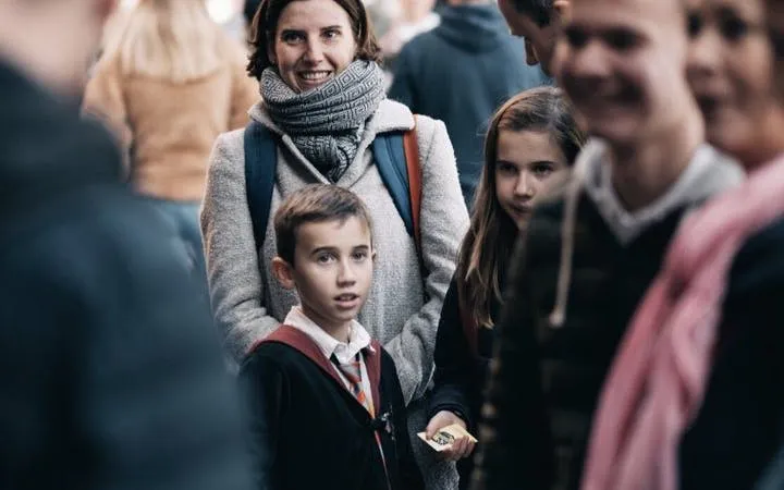 Group of people on a Harry Potter walking tour in London, child holding souvenir.