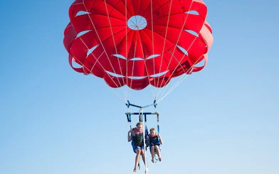 Parasailing over the Red Sea with a red parachute, Hurghada adventure.