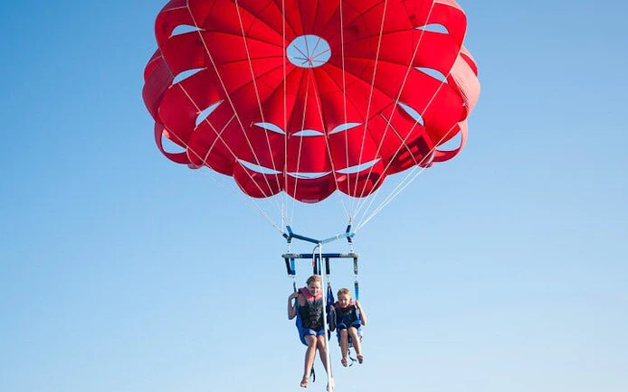 Parasailing over the Red Sea with a red parachute, Hurghada adventure.