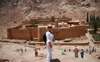 Saint Catherine Monastery with tourists, Sinai mountains backdrop, part of guided tour from Sharm El Sheikh.