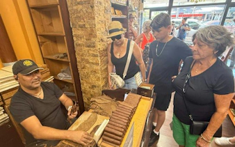 Cigar maker demonstrating rolling techniques to tourists in Little Havana, Miami.