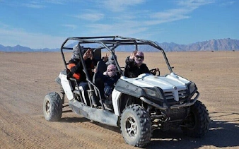 Family enjoying buggy ride in Sharm El Sheikh desert with mountains in background.