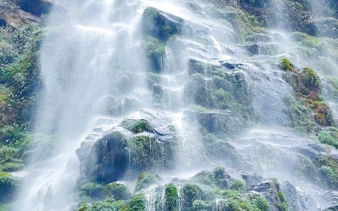 Queen Bee Waterfall cascading over rocks in Sapa jungle trek tour.