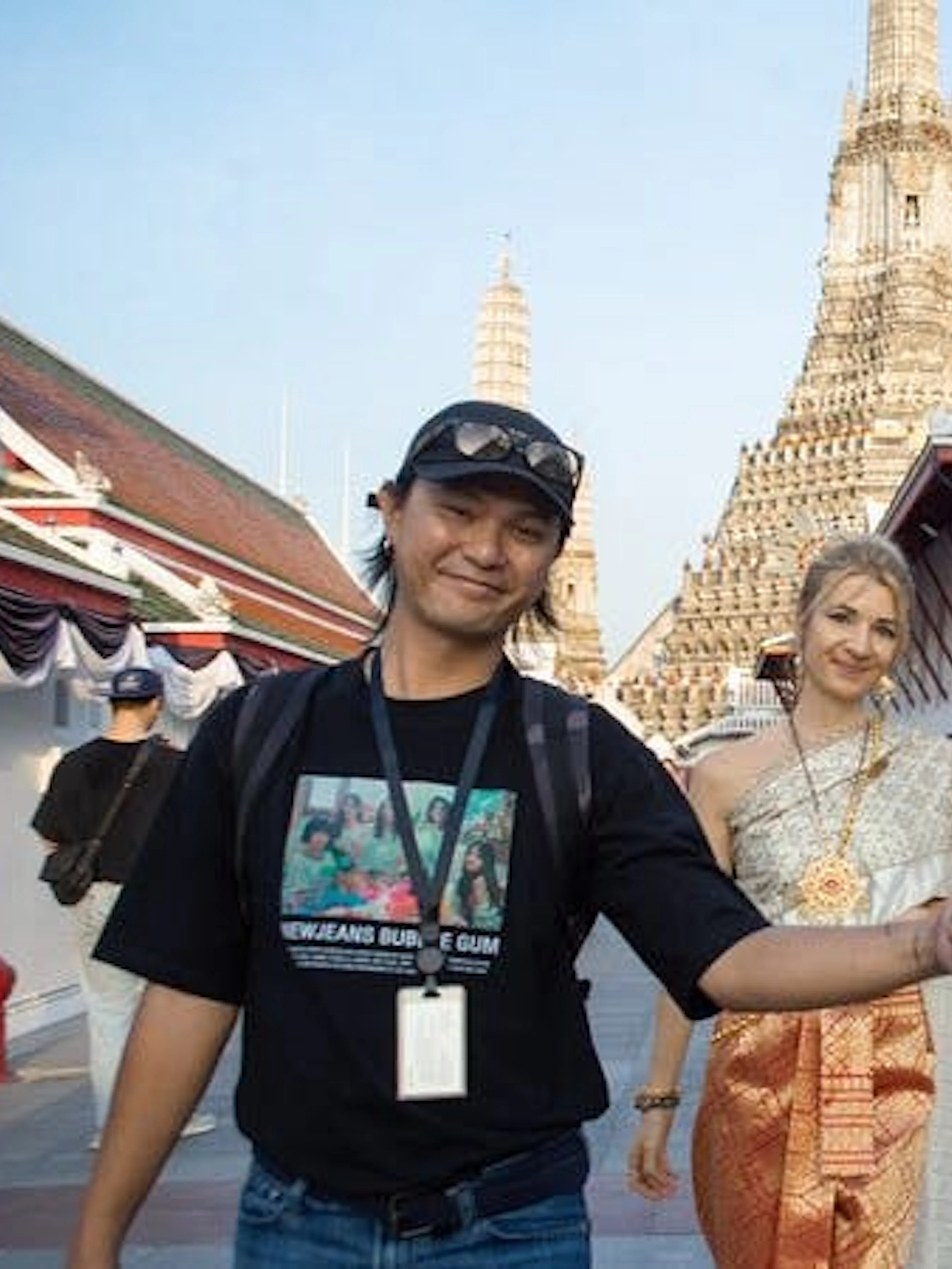 Tourists in traditional Thai costumes walking near Wat Arun in Bangkok.