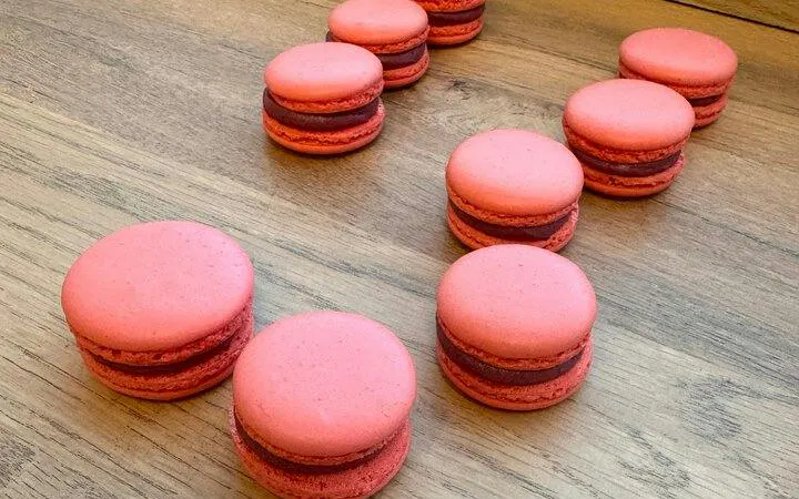 Pink macarons on a wooden table during a Paris baking class with a Le Cordon Bleu-trained chef.