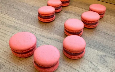 Pink macarons on a wooden table during a Paris baking class with a Le Cordon Bleu-trained chef.