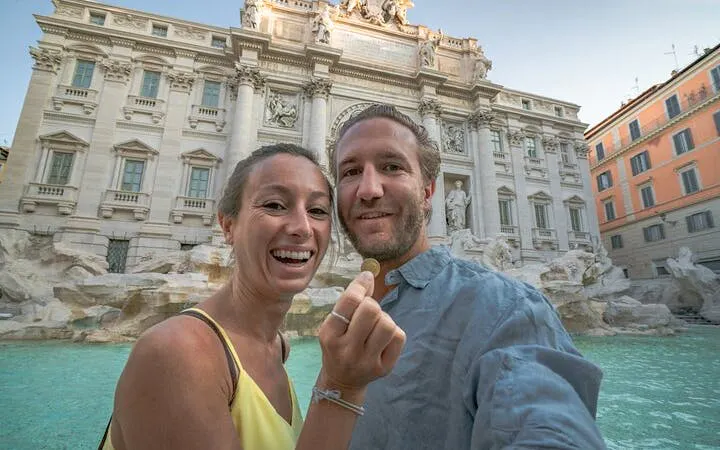 Couple holding a coin in front of the Trevi Fountain in Rome.