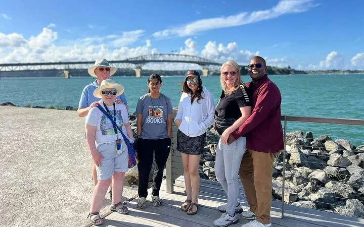 Group of tourists on Auckland City Half Day Tour with Auckland Harbour Bridge in background.