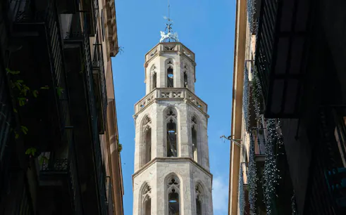 Santa Maria del Mar bell tower between narrow streets in El Born, Barcelona.