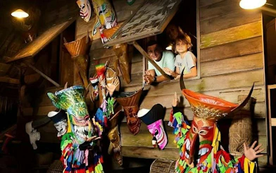 Performers in traditional costumes at Siam Niramit Phuket show, with colorful masks and wooden backdrop.