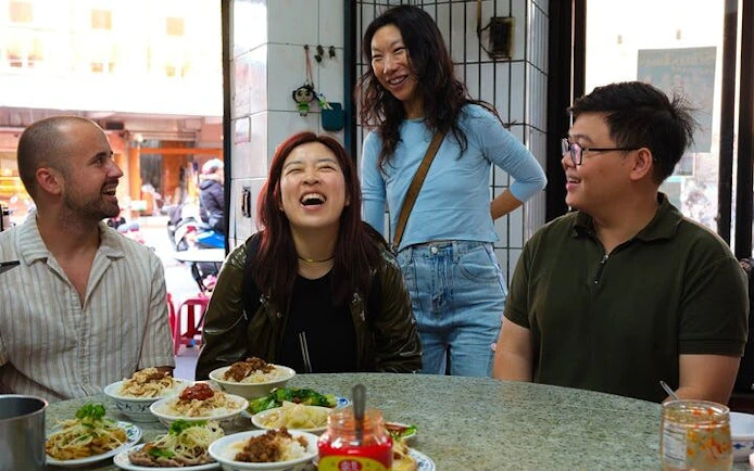 Locals and tourists enjoying a meal at a Taipei food tour with various traditional dishes.