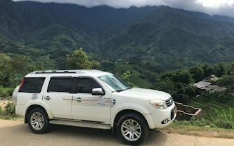 Private car parked with view of Sapa mountains, Vietnam, for transfer to Ha Noi.