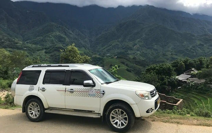 Private car parked with view of Sapa mountains, Vietnam, for transfer to Ha Noi.