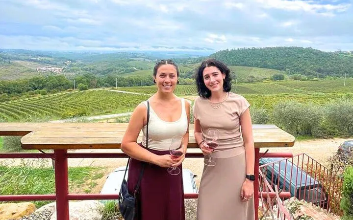 Two people enjoying wine with a view of Chianti vineyards in Tuscany.