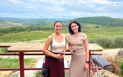 Two people enjoying wine with a view of Chianti vineyards in Tuscany.