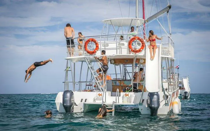 Catamaran with people snorkeling, diving, and using a slide in Punta Cana.