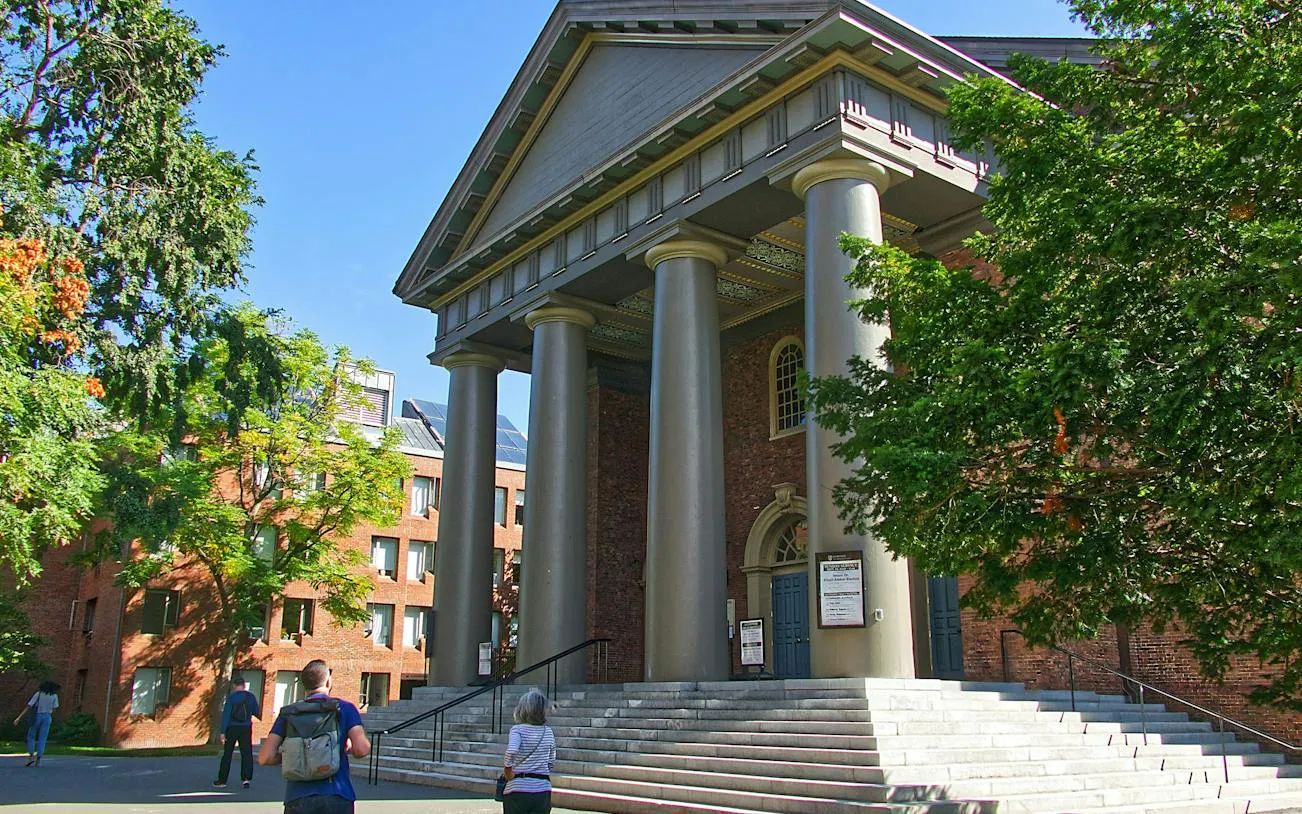 Harvard Yard building with columns and visitors, part of self-guided audio walk in Boston.
