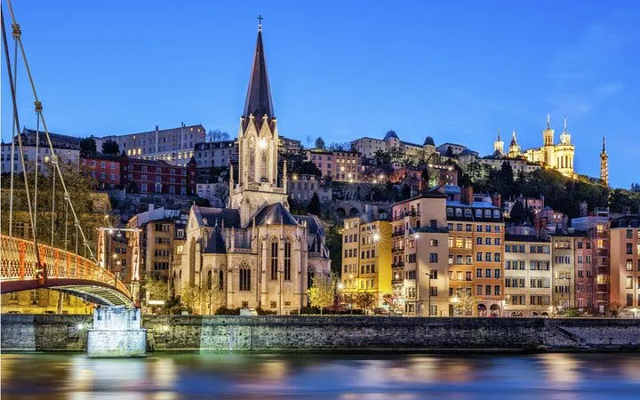 Lyon cityscape with Saint George Church and Basilica of Notre-Dame de Fourvière at dusk.