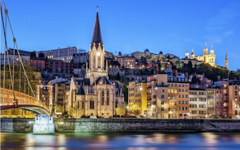 Lyon cityscape with Saint George Church and Basilica of Notre-Dame de Fourvière at dusk.
