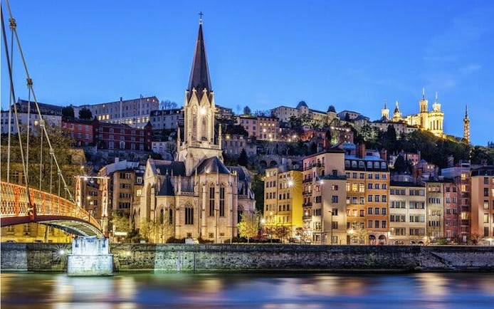 Lyon cityscape with Saint George Church and Basilica of Notre-Dame de Fourvière at dusk.