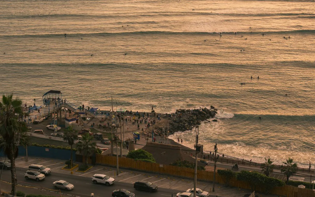 Barranco coastline with surfers and people on the pier during a self-guided audio walking tour in Lima.