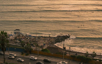 Barranco coastline with surfers and people on the pier during a self-guided audio walking tour in Lima.