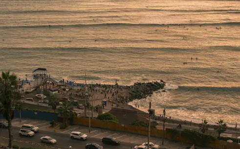 Barranco coastline with surfers and people on the pier during a self-guided audio walking tour in Lima.