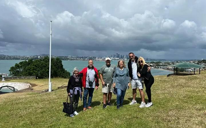 Group enjoying Auckland city view from hilltop during half-day sightseeing tour.