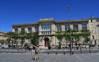 Marseille city square with historic building and tourists exploring.