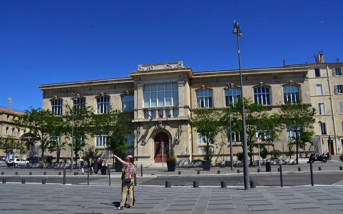 Marseille city square with historic building and tourists exploring.