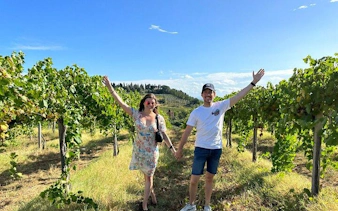 Couple walking through vineyard on Pisa, Vinci, and Tuscan Winery tour.