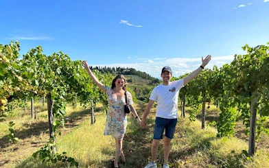 Couple walking through vineyard on Pisa, Vinci, and Tuscan Winery tour.