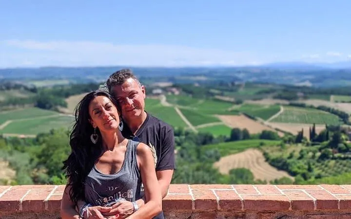 Couple enjoying scenic view of Tuscany vineyards on a sunny day.