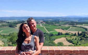 Couple enjoying scenic view of Tuscany vineyards on a sunny day.